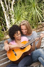 Young couple in park, woman playing guitar. Photo: Rob Lewine
