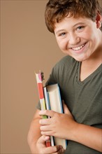 Studio portrait of boy (12-13) holding books. Photo: Rob Lewine