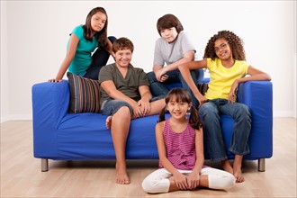 Group of children (10-11, 12-13) sitting on sofa, studio shot. Photo : Rob Lewine