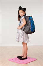 Studio portrait of girl (8-9) carrying backpack. Photo : Rob Lewine