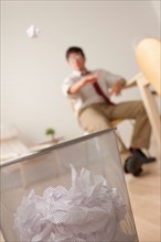 Businessman tossing ball of paper into wastebasket. Photo: Rob Lewine