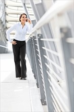 Young businesswoman on walkway, using cell phone. Photo: Take A Pix Media
