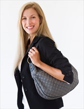 Studio portrait of mid adult woman carrying bag.