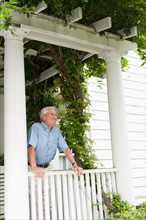 Senior man standing on porch.