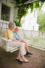 Grandmother and grandson (10-11) sitting on porch swing.