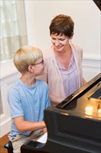 Mother and son (10-11) playing grand piano.