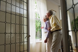 Senior couple looking through window.