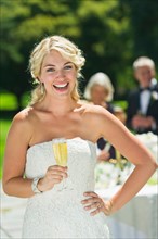 Portrait of bride holding champagne flute.