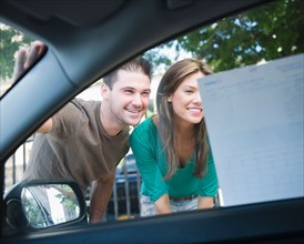 Smiling couple riding advertisement on car window. Photo : Jamie Grill