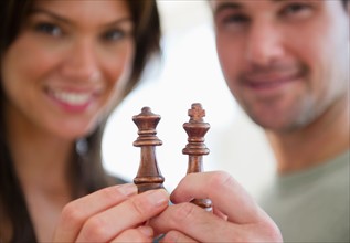 Smiling couple showing chess pieces. Photo : Jamie Grill