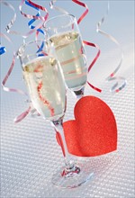 Flutes with champagne and red paper heart, close-up. Photo : Daniel Grill