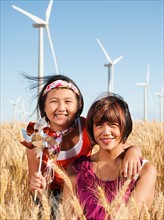 USA, Oregon, Wasco, Portrait of two girls (10-11, 12-13) standing in wheat field, wind turbines in