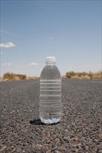 Water bottle sitting in middle of desert road. Photo : Winslow Productions