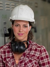 Female in hard hat and ear protectors in industrial setting. Photo: db2stock