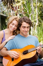 Young couple in park, man playing guitar. Photo: Rob Lewine