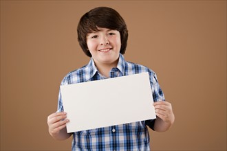 Studio portrait of boy (10-11) holding blank sheet of paper. Photo : Rob Lewine