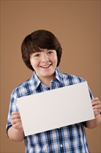 Studio portrait of boy (10-11) holding blank sheet of paper. Photo: Rob Lewine