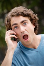 Portrait of young man talking on phone, with facial expression. Photo: Rob Lewine
