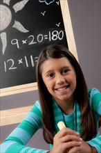 Studio portrait of girl (8-9) next to blackboard. Photo : Rob Lewine