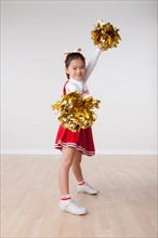 Studio portrait of girl (8-9) cheerleading. Photo : Rob Lewine