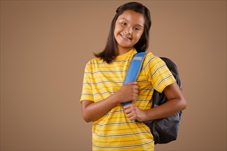 Studio portrait of girl (10-11) wearing backpack. Photo: Rob Lewine