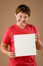 Studio portrait of boy (12-13) holding blank sheet of paper. Photo: Rob Lewine