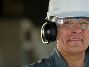 Portrait of industrial worker wearing hard hat and ear protectors. Photo: db2stock