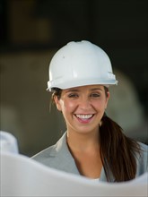 Woman wearing hardhat reading blueprint. Photo : db2stock