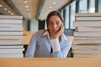 Portrait of female student between stacks of books. Photo: Jan Scherders