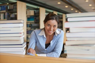 Portrait of female student between stacks of books. Photo: Jan Scherders