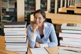 Portrait of female student with books in library. Photo : Jan Scherders