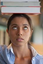 Portrait of female student balancing stack of books on head. Photo: Jan Scherders