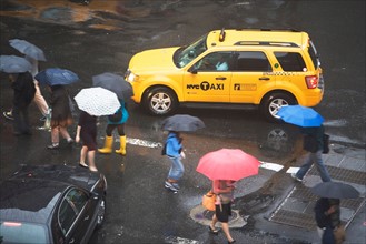USA, New York State, New York City, Manhattan, Yellow taxi cab on street, pedestrians walking with