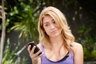 Young woman text-messaging, with facial expression. Photo : Rob Lewine