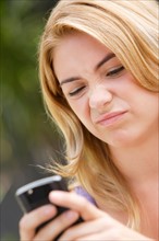 Young woman text-messaging, with facial expression. Photo: Rob Lewine