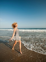 Attractive young woman walking on sandy beach. Photo: Erik Isakson