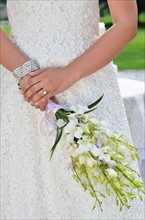 Bride holding wedding bouquet, midsection.