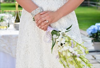 Bride holding wedding bouquet, midsection.