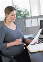 Young pregnant woman working in office.