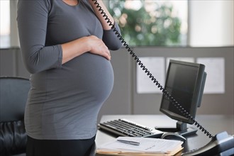 Young pregnant woman working in office.