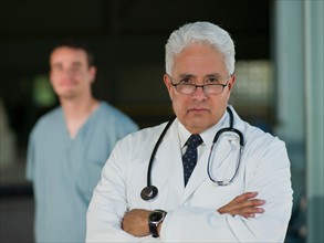 Portrait of senior doctor with orderly in background. Photo: db2stock