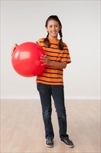 Studio portrait of girl (8-9) holding red ball. Photo: Rob Lewine