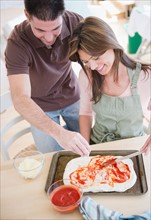 Smiling couple preparing pizza. Photo : Jamie Grill