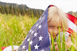 Portrait of boy (6-7) wrapped in American flag. Photo: Shawn O'Connor