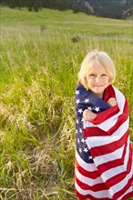 Portrait of boy (6-7) wrapped in American flag. Photo: Shawn O'Connor