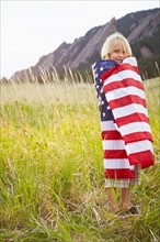 Portrait of boy (6-7) wrapped in American flag. Photo: Shawn O'Connor