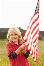 Portrait of boy (6-7) waving American flag. Photo: Shawn O'Connor