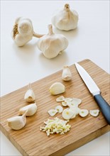 Studio shot of fresh garlic being chopped on cutting board.
