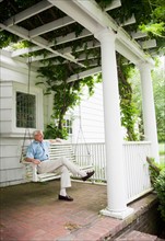 Senior man sitting on porch swing.