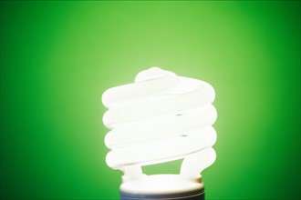 Studio shot of energy efficient lightbulb on green background.